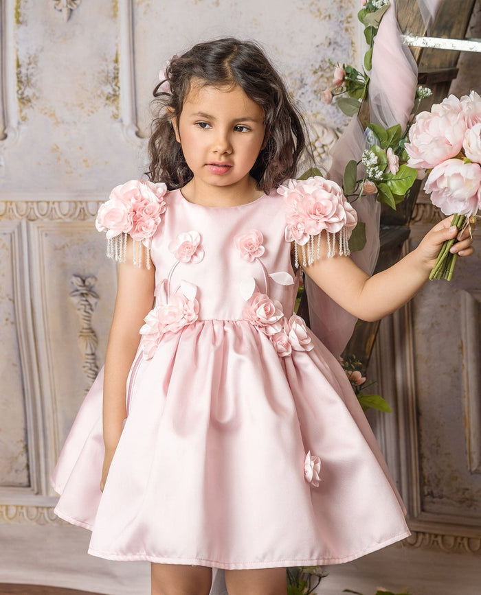 Blush pink girls dress with textured fabric, floral embellishments, and a flowy skirt silhouette