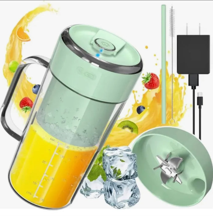 A mint green electric juicer blender pitcher with a clear container, shown alongside its lid, a cleaning brush, and a black power adapter on a white background with orange juice, strawberries, kiwi, and ice cubes.